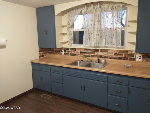 kitchen featuring open shelves, light countertops, visible vents, backsplash, and a sink