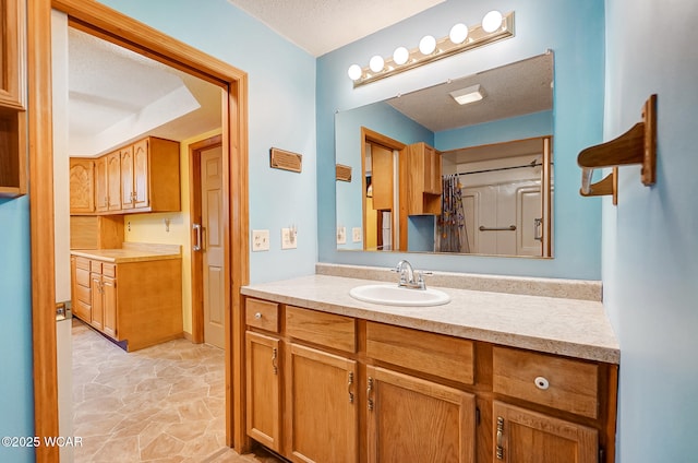 full bath with stone finish flooring, vanity, and a textured ceiling