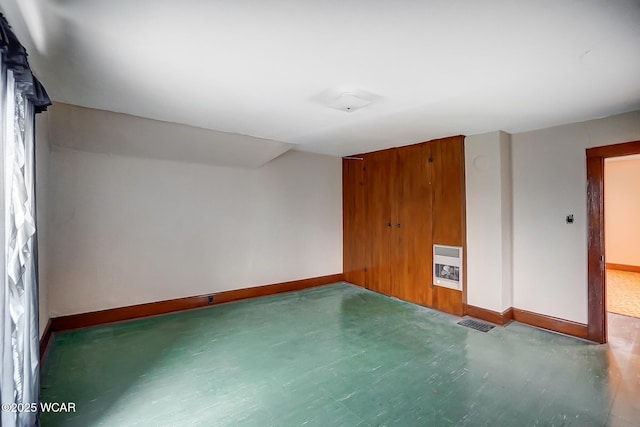 spare room featuring heating unit, baseboards, and visible vents