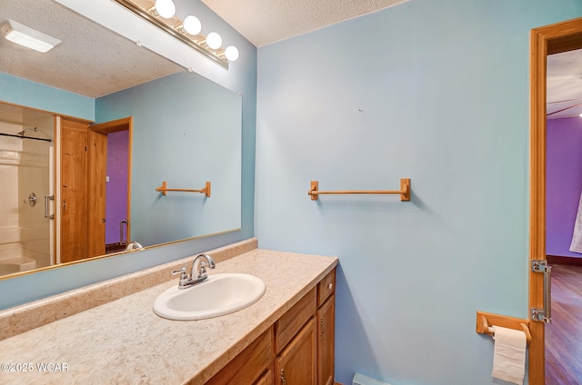 bathroom featuring a shower, vanity, visible vents, and a textured ceiling