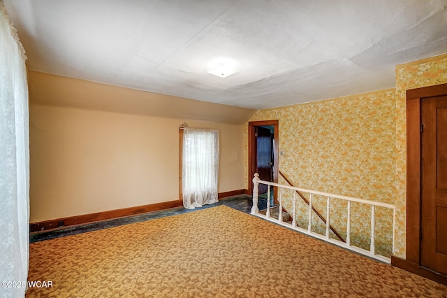 spare room with wallpapered walls and baseboards