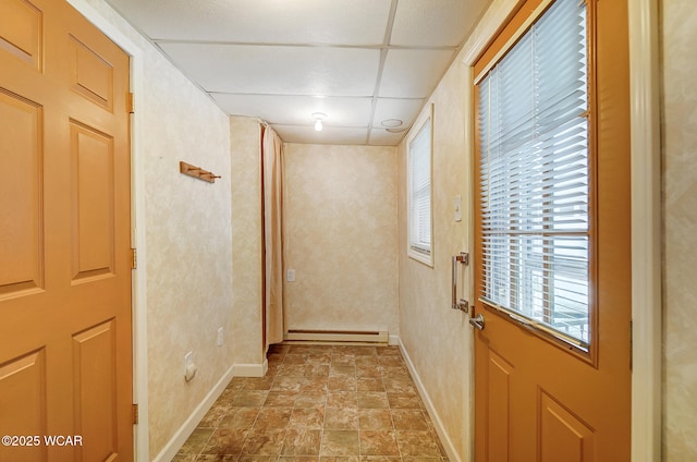 entryway with a baseboard radiator, stone finish flooring, baseboards, and a paneled ceiling