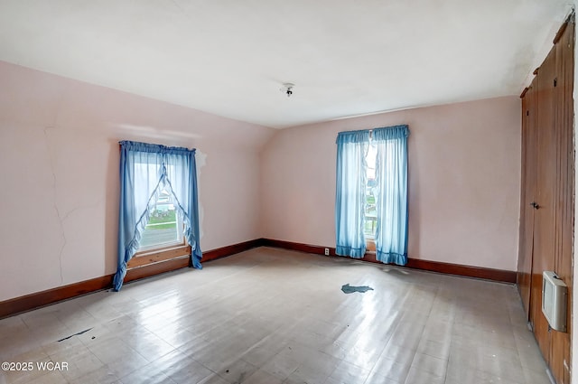 unfurnished room featuring baseboards, vaulted ceiling, and plenty of natural light