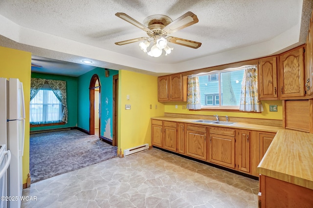 kitchen with light countertops, freestanding refrigerator, a textured ceiling, a sink, and a baseboard radiator