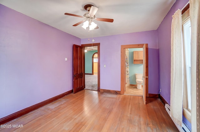 unfurnished bedroom with ensuite bath, baseboards, light wood finished floors, and baseboard heating