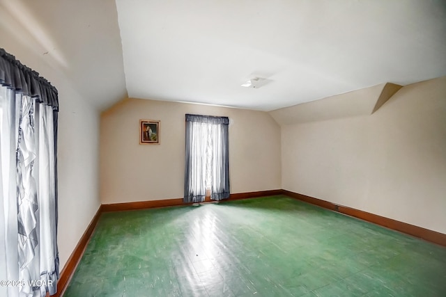 additional living space with baseboards and vaulted ceiling