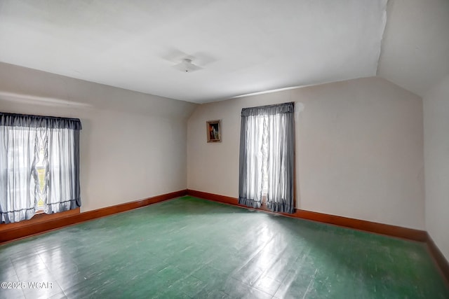 unfurnished room with baseboards, lofted ceiling, and a wealth of natural light