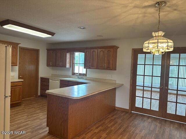 1461 Cessna Ave, Lima, OH 45807 - kitchen with wood finished floors, light countertops, white appliances, baseboards, and a peninsula