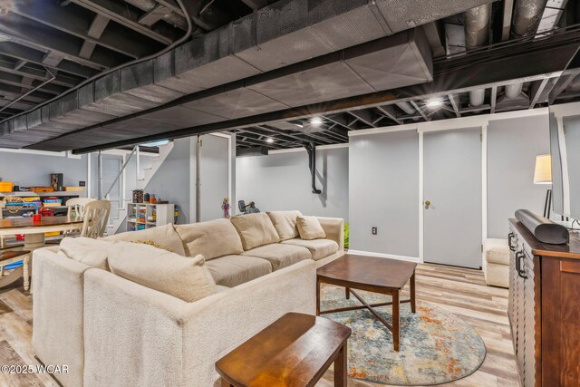 living room featuring baseboards, wood finished floors, and stairs
