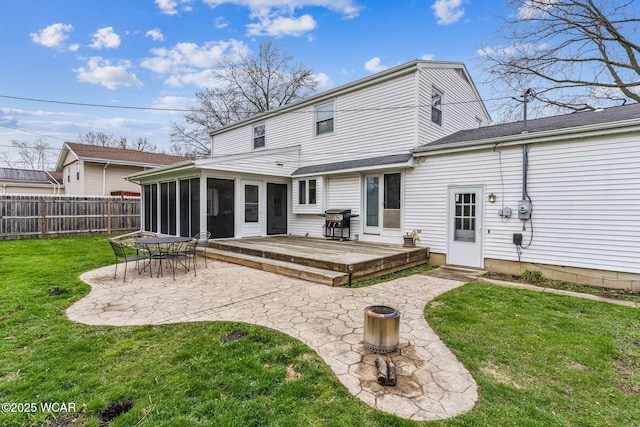 back of house with a patio, a sunroom, a wooden deck, a yard, and fence
