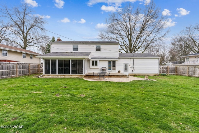 rear view of house featuring a fenced backyard, a chimney, a sunroom, and a lawn