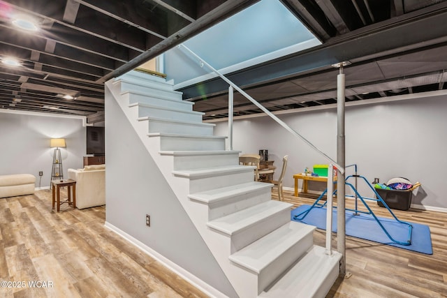 finished basement featuring stairway, baseboards, and wood finished floors