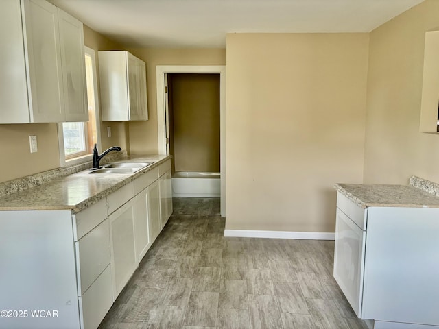 514 Fairview Ave, Lima, OH 45804 - kitchen with a sink, light countertops, baseboards, and white cabinetry
