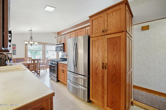 216 N Rauthland Ave, Wapakoneta, OH 45895 - kitchen with appliances with stainless steel finishes, light countertops, a sink, brown cabinets, and decorative light fixtures
