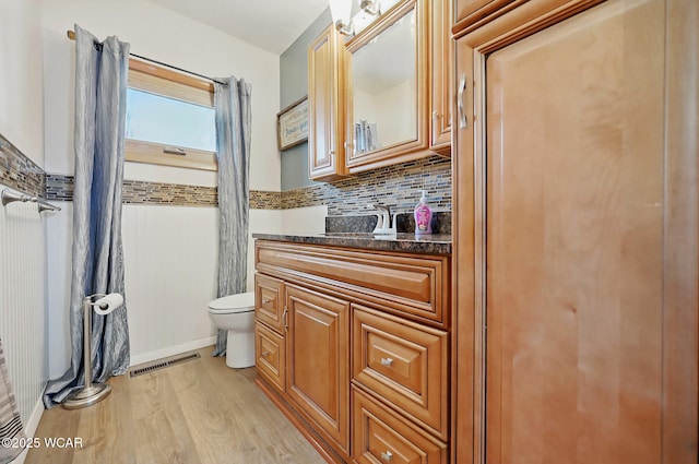 216 N Rauthland Ave, Wapakoneta, OH 45895 - bathroom featuring toilet, wood finished floors, vanity, and backsplash