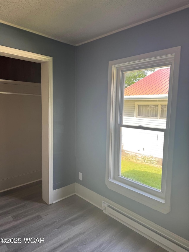 809 King St, Kenton, OH 43326 - unfurnished bedroom featuring baseboard heating, dark wood-style floors, and a closet