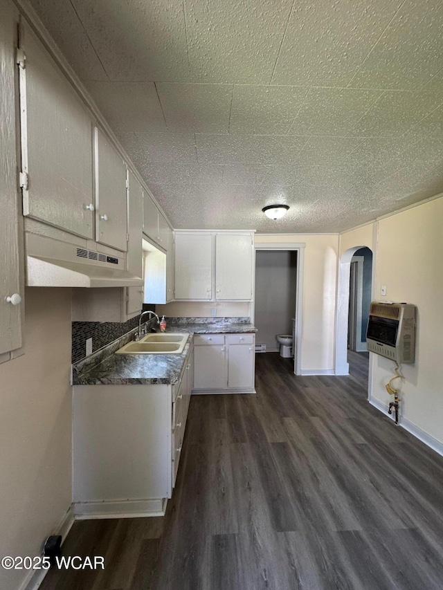 809 King St, Kenton, OH 43326 - kitchen featuring heating unit, arched walkways, dark wood-style floors, under cabinet range hood, and white cabinetry