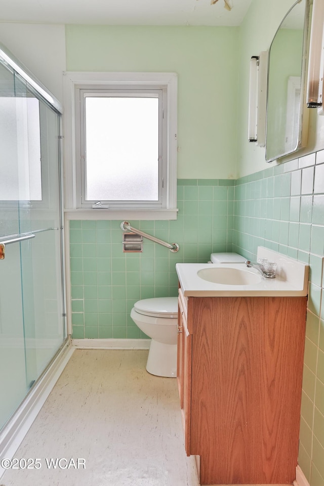 bathroom with a stall shower, wainscoting, tile walls, and vanity