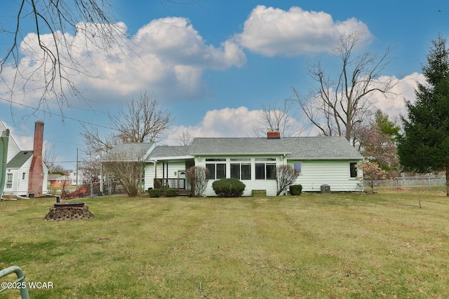 view of front of home with central AC, a shingled roof, fence, a chimney, and a front yard