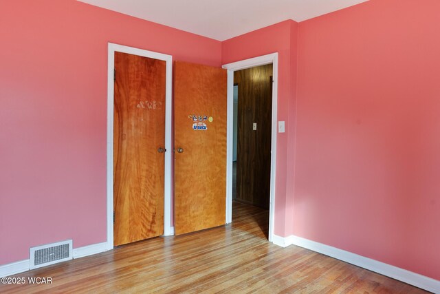 empty room featuring baseboards, visible vents, and wood finished floors