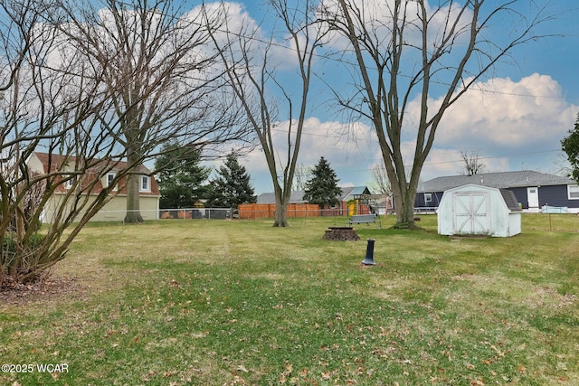 view of yard with a fire pit, a storage unit, an outdoor structure, and fence