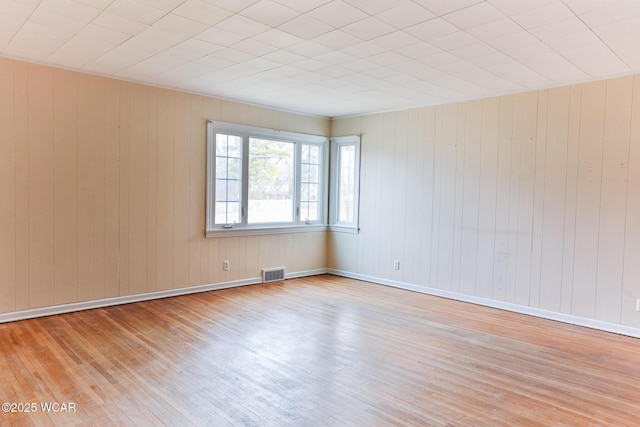 spare room with light wood-type flooring, visible vents, and baseboards