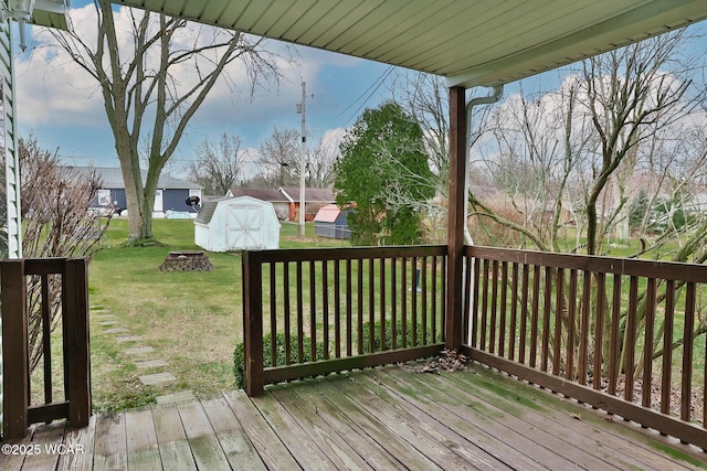 deck featuring a yard, a shed, an outdoor fire pit, and an outdoor structure