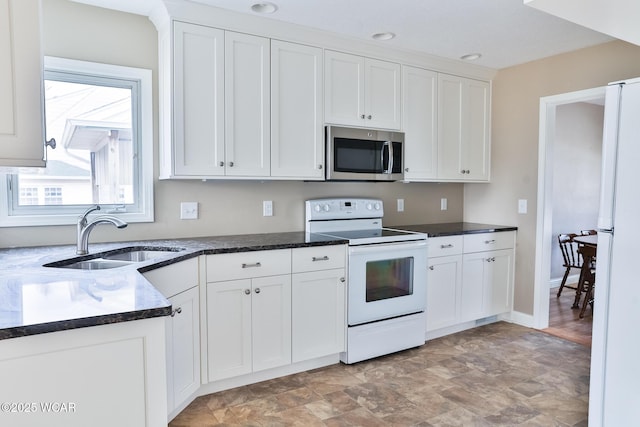 kitchen with white appliances, a sink, white cabinetry, and baseboards