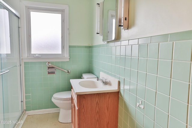 bathroom with tile walls, a shower stall, toilet, and vanity