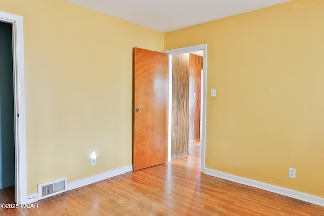 unfurnished room featuring baseboards, visible vents, and hardwood / wood-style floors