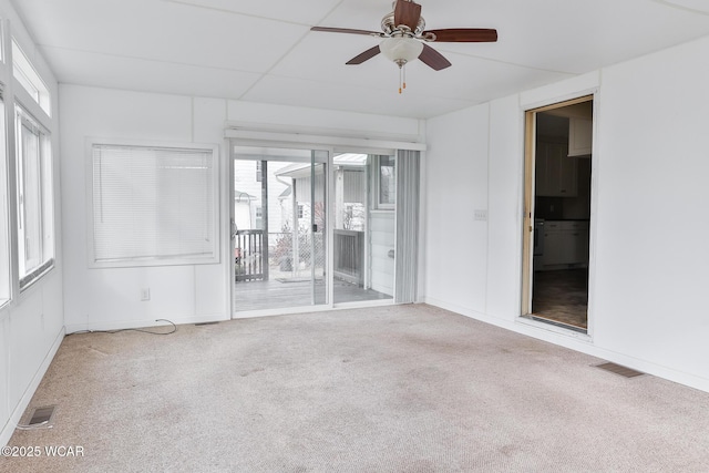 empty room featuring carpet flooring, ceiling fan, visible vents, and baseboards