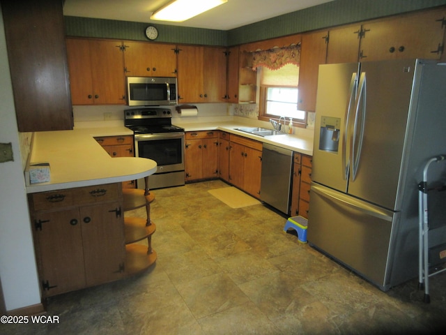 kitchen featuring light countertops, stainless steel appliances, brown cabinetry, and a sink
