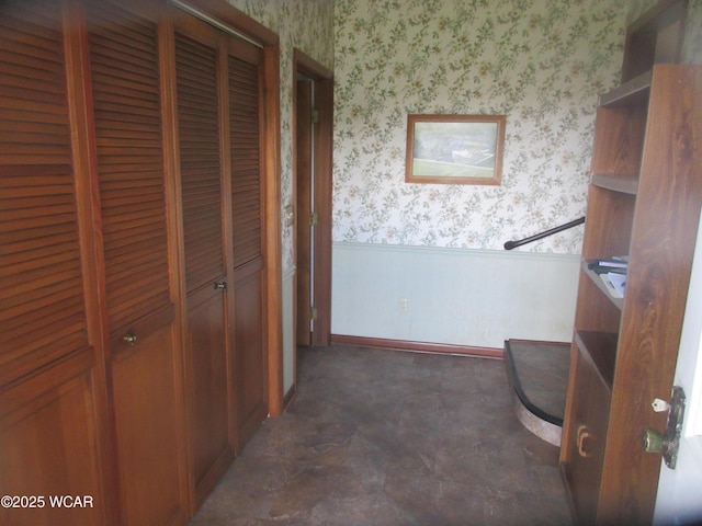 hallway featuring a wainscoted wall and wallpapered walls