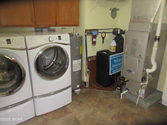 clothes washing area featuring washing machine and clothes dryer, water heater, cabinet space, and heating unit