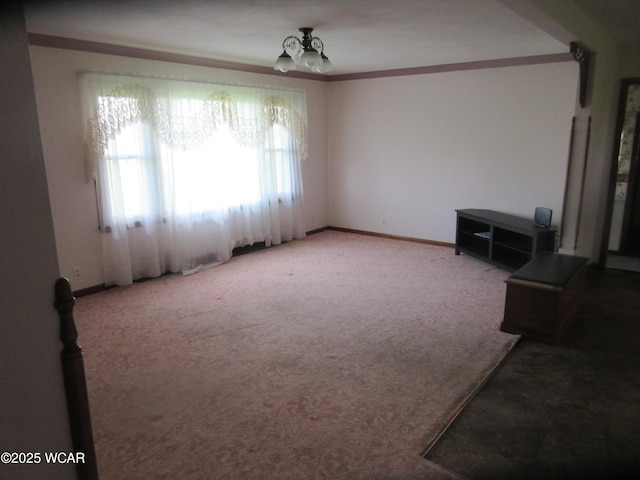 interior space featuring carpet flooring, a chandelier, baseboards, and ornamental molding