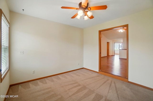 carpeted empty room featuring a ceiling fan and baseboards