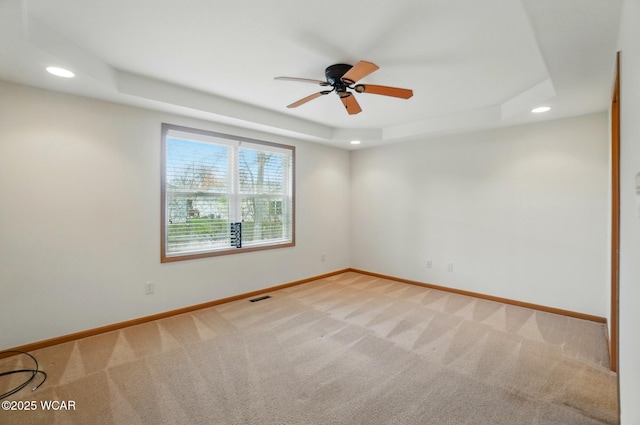 spare room with carpet floors, a tray ceiling, baseboards, visible vents, and recessed lighting