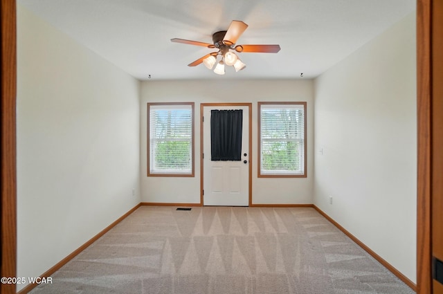 unfurnished room with baseboards, a wealth of natural light, and light carpet