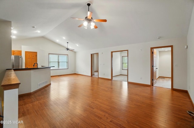 unfurnished living room with ceiling fan, vaulted ceiling, visible vents, and plenty of natural light