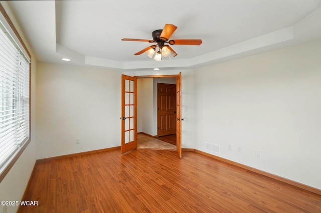 empty room with recessed lighting, a tray ceiling, visible vents, light wood-type flooring, and ceiling fan