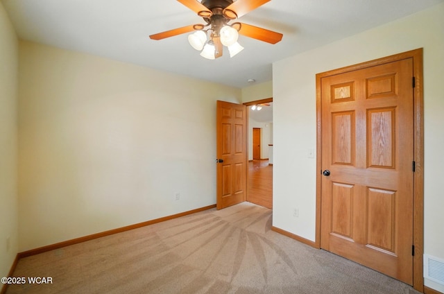 unfurnished bedroom featuring light colored carpet, baseboards, and a ceiling fan
