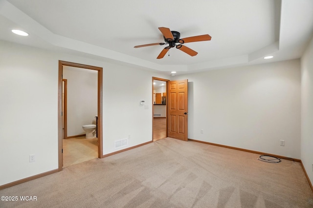 unfurnished bedroom with visible vents, a tray ceiling, recessed lighting, and light colored carpet
