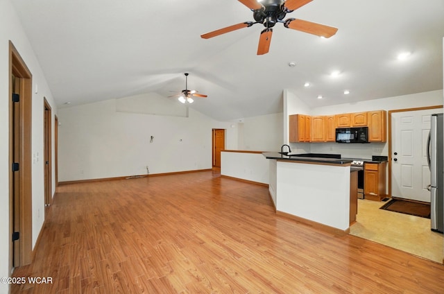 kitchen featuring vaulted ceiling, dark countertops, ceiling fan, a peninsula, and appliances with stainless steel finishes