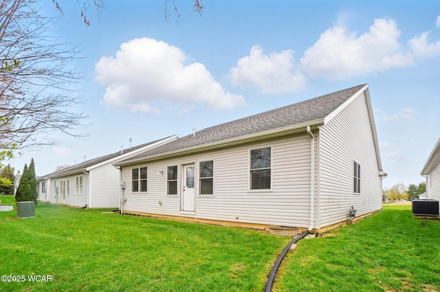 back of house with cooling unit and a lawn