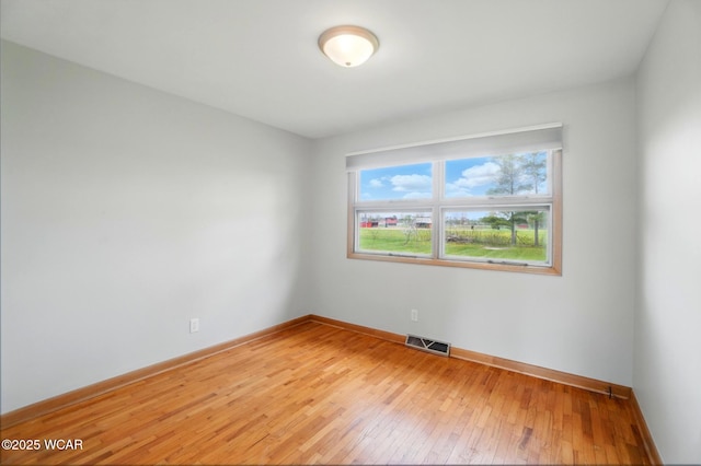 empty room featuring light wood finished floors, visible vents, and baseboards