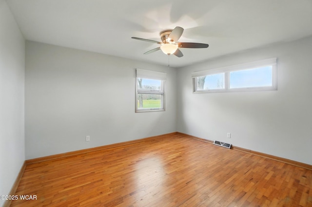 unfurnished room featuring light wood-type flooring, visible vents, a ceiling fan, and baseboards