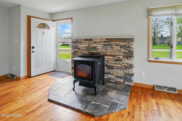 entryway featuring visible vents, a wood stove, wood-type flooring, and plenty of natural light