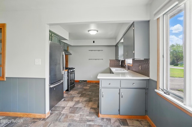 kitchen with appliances with stainless steel finishes, plenty of natural light, under cabinet range hood, and gray cabinets