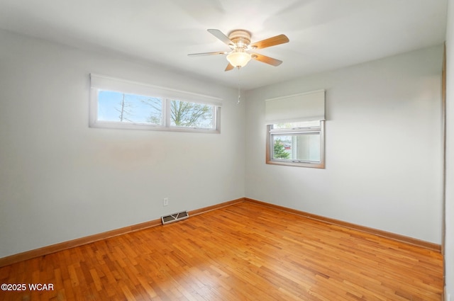 spare room with a ceiling fan, visible vents, baseboards, and light wood-style floors