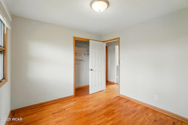 unfurnished bedroom with light wood finished floors, a closet, and baseboards